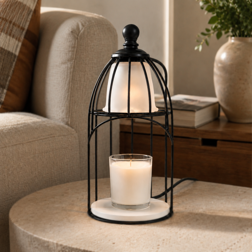 Vintage cage candle warmer illuminated on a round stone table beside a cream armchair and ceramic vase.