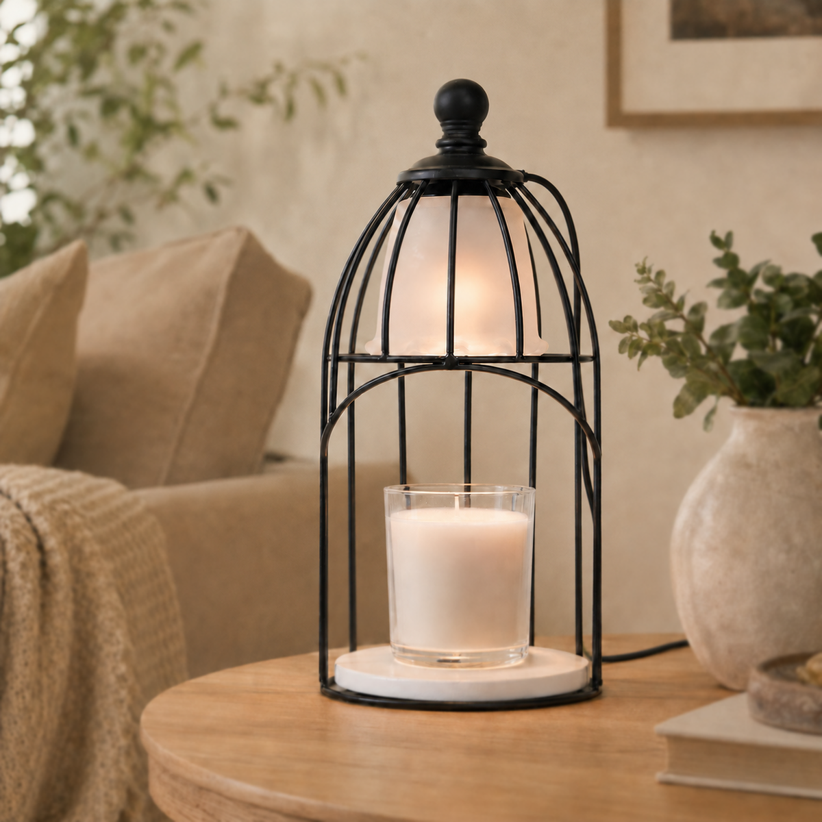Vintage birdcage electric candle warmer glowing over a white jar candle on a light wood side table beside a sofa.