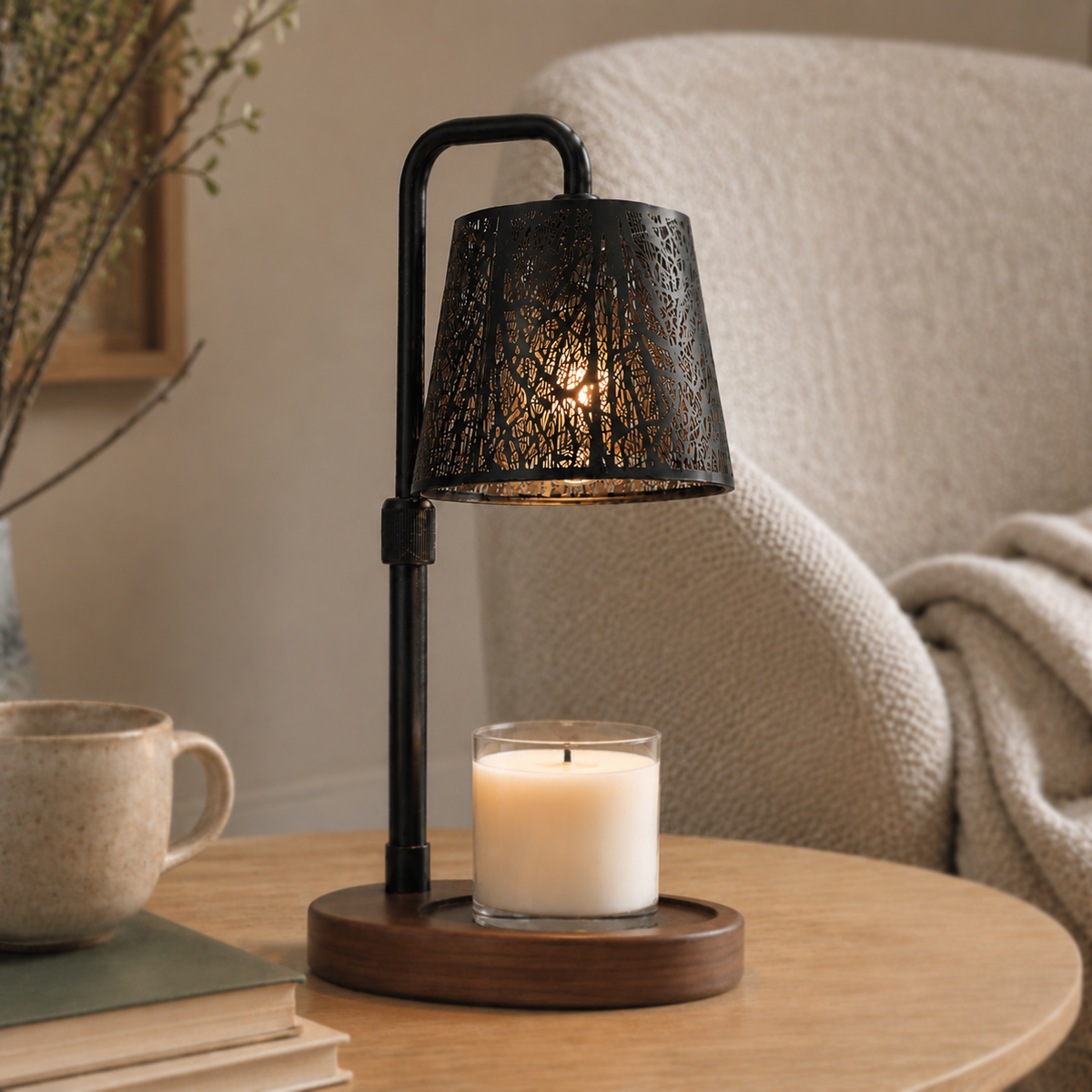 Black forest candle warmer glowing over a white jar candle beside an armchair, mug and stacked books.