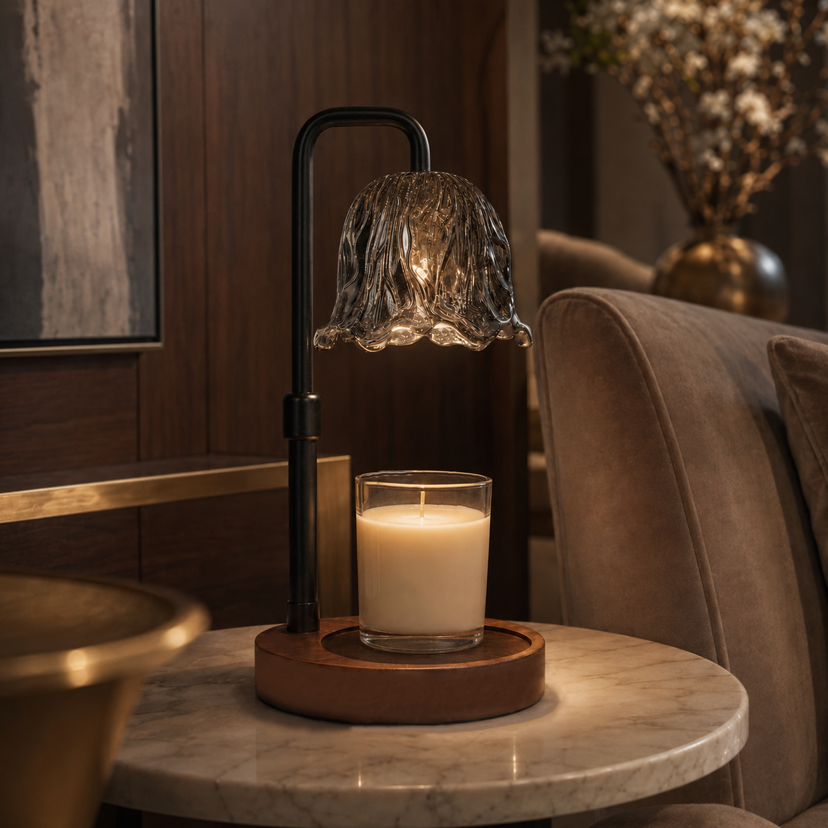Smoked glass candle warmer illuminated on a round marble side table beside a brown upholstered chair.