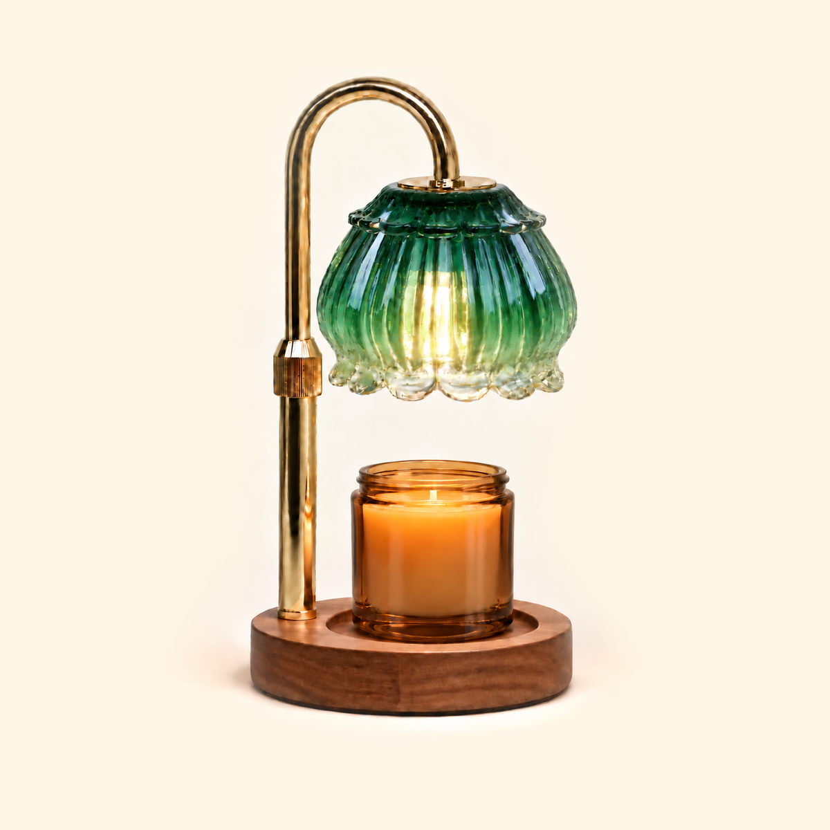 Emerald green glass candle warmer lamp warming an amber jar candle on a warm cream background