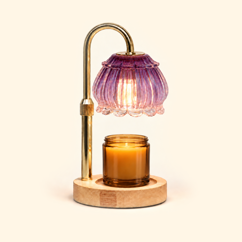 Amethyst purple glass candle warmer lamp warming an amber jar candle on a cream background