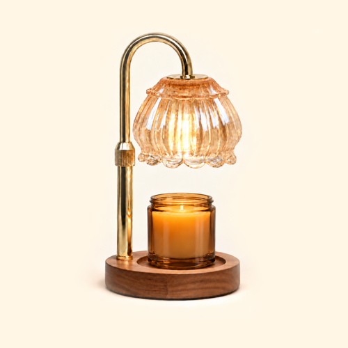 Champagne glass candle warmer lamp warming an amber jar candle on a warm cream background