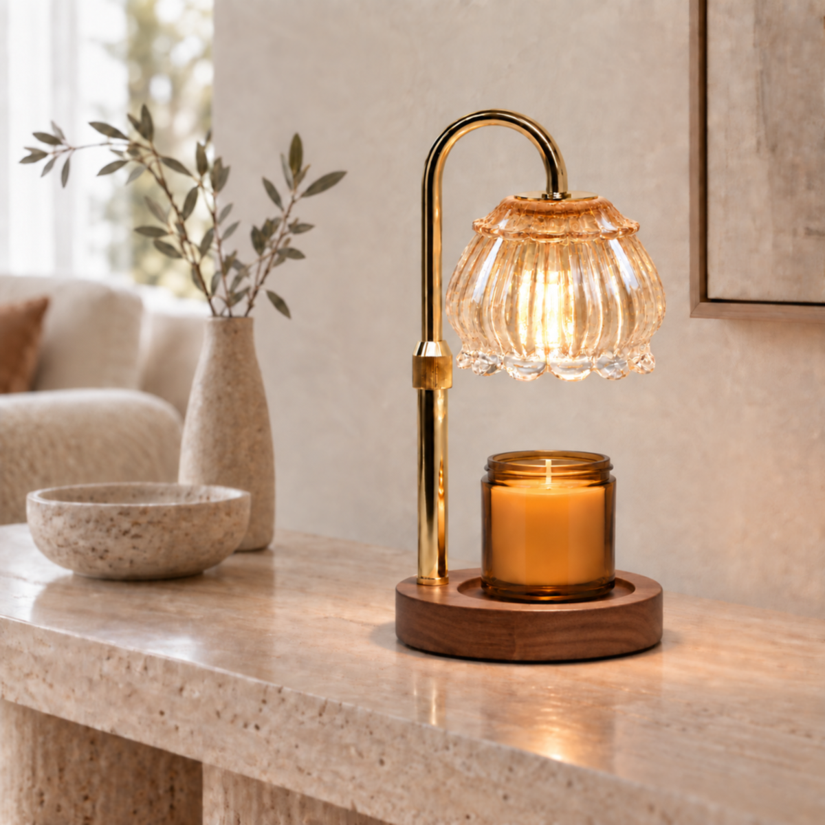 Champagne glass candle warmer lamp with gold arm styled on a neutral living room console