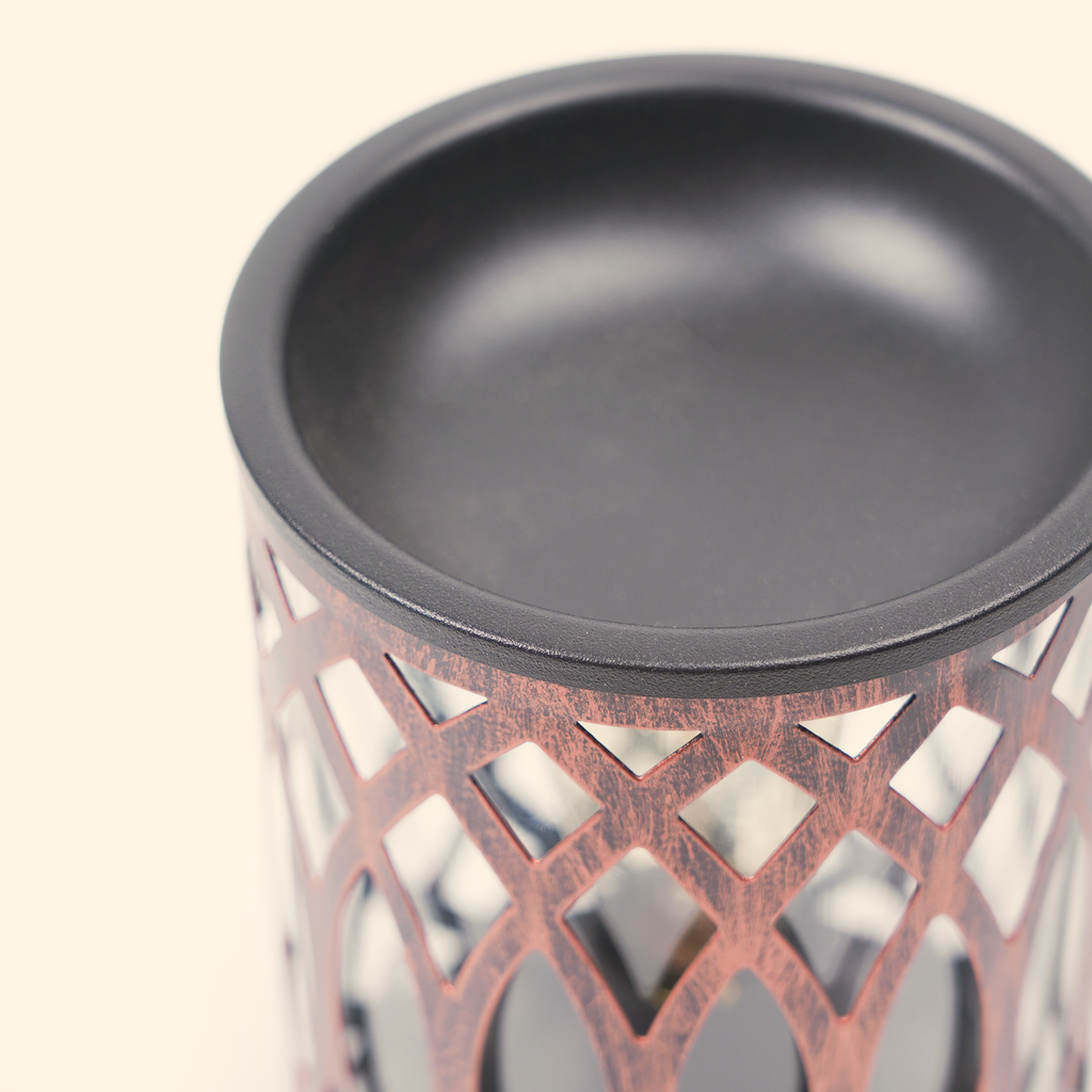 Close-up of the black warming dish and antique bronze openwork frame on the Mesh Lantern wax warmer.