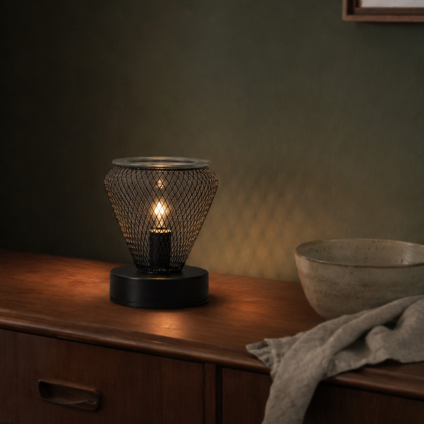 Black vase-shaped wax warmer illuminated on a dark wooden sideboard with neutral decor.