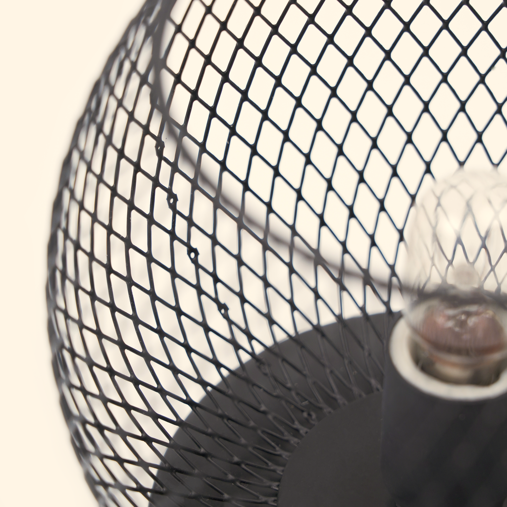 Close-up of the unlit clear bulb and black metal diamond lattice on the globe wax warmer.