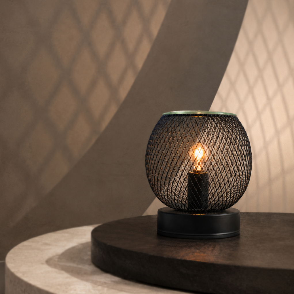 Black lattice globe wax warmer glowing on a stone pedestal and casting geometric shadows on the wall.