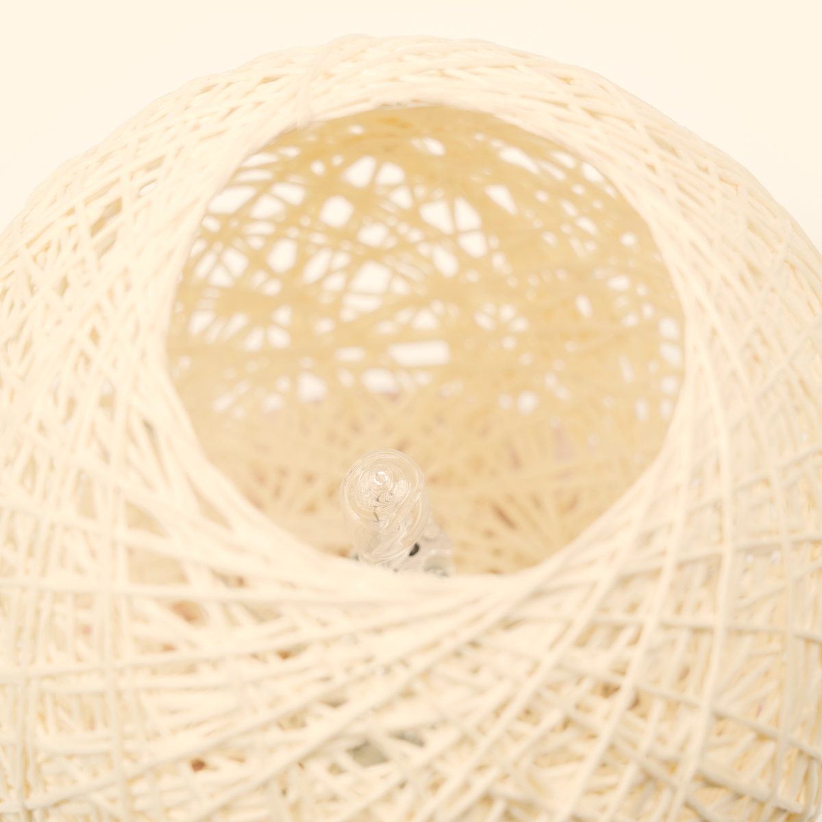 Close-up inside the woven globe showing the unlit clear bulb and layered hand-wrapped fiber texture.