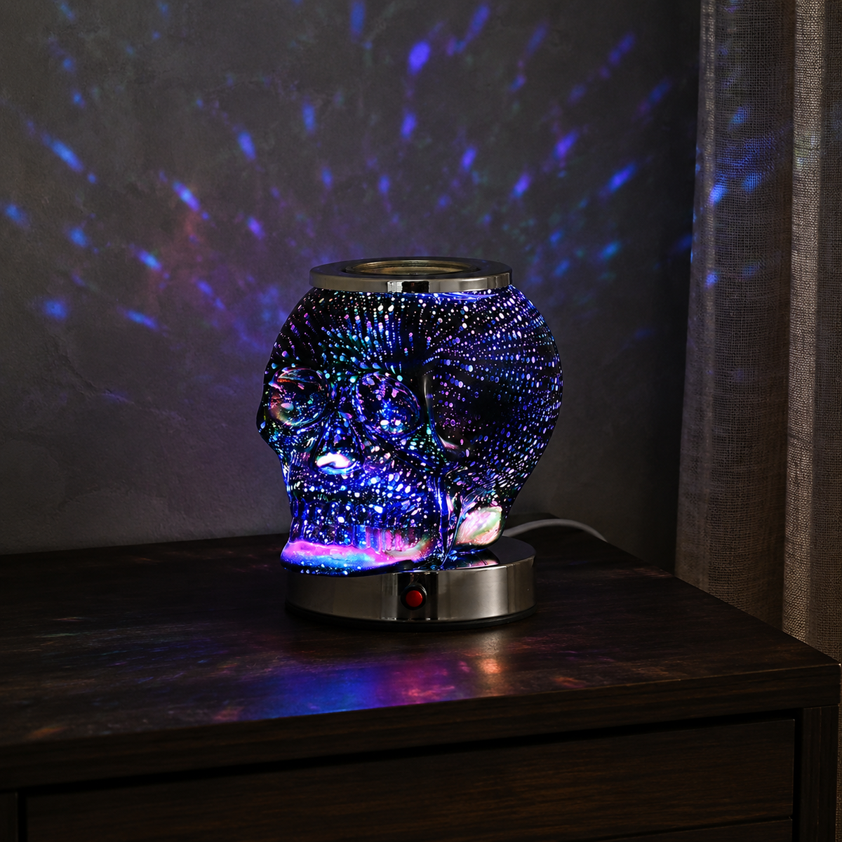 Illuminated Halloween skull wax warmer displayed beside pumpkins and autumn leaves on a dark wooden table.
