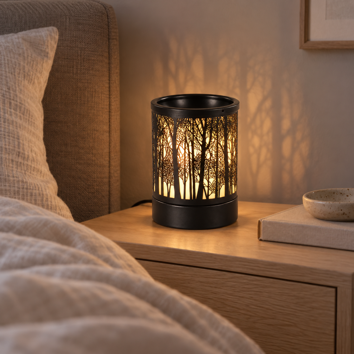 Illuminated forest cutout wax warmer on a bedside table in a softly lit neutral bedroom