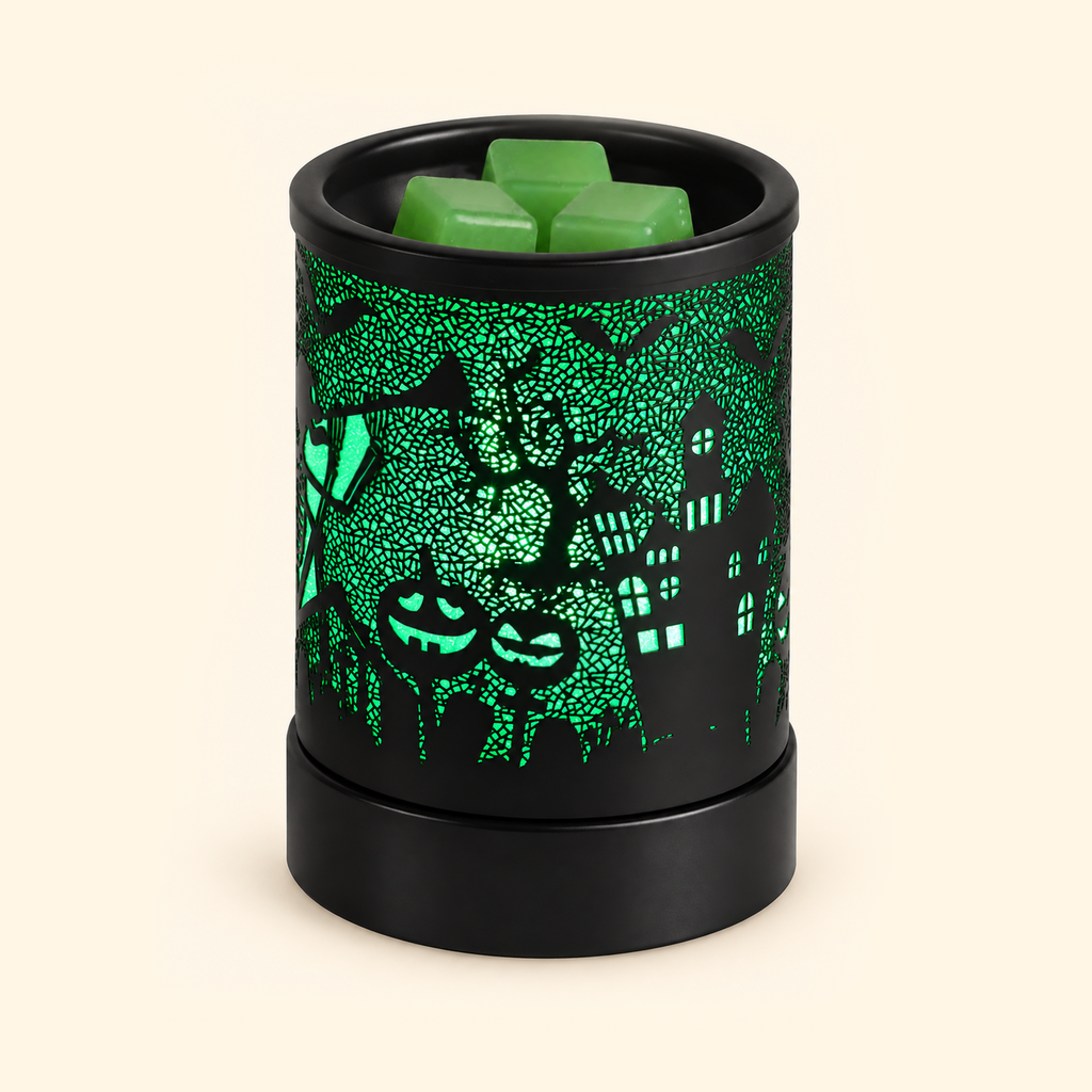 Black Halloween wax melt warmer glowing green with haunted house, tree, bats and jack-o’-lantern cutouts.