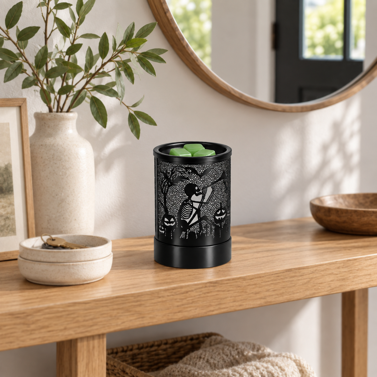 Unlit black Halloween wax melt warmer with skeleton design displayed on an entryway console table.