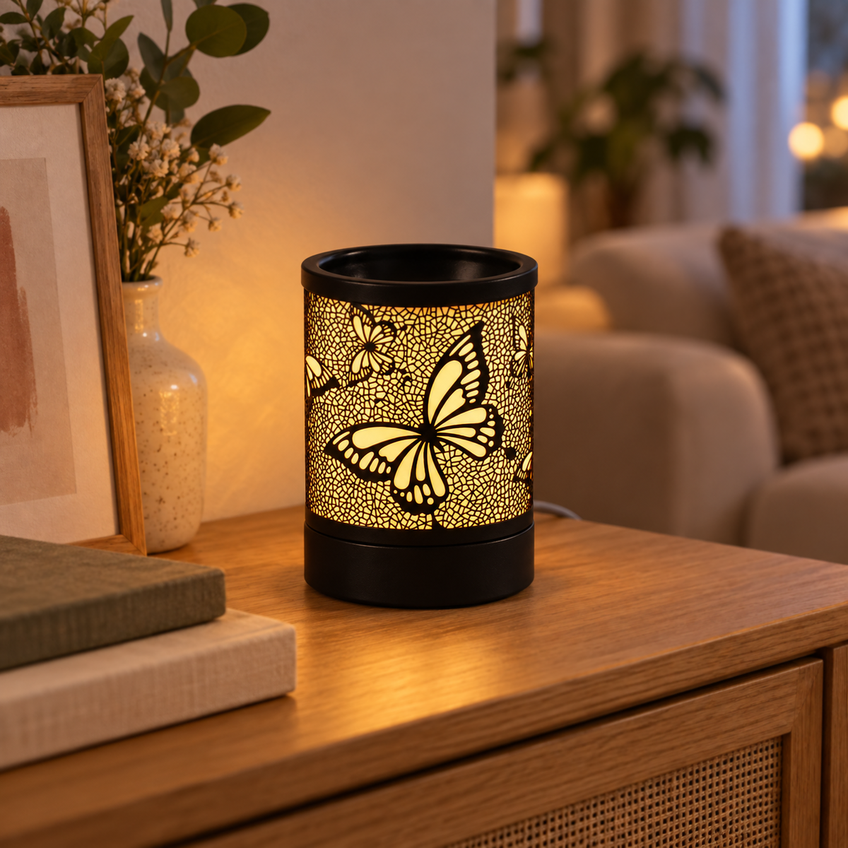 Black butterfly wax warmer glowing on an oak living room console beside books and framed artwork.