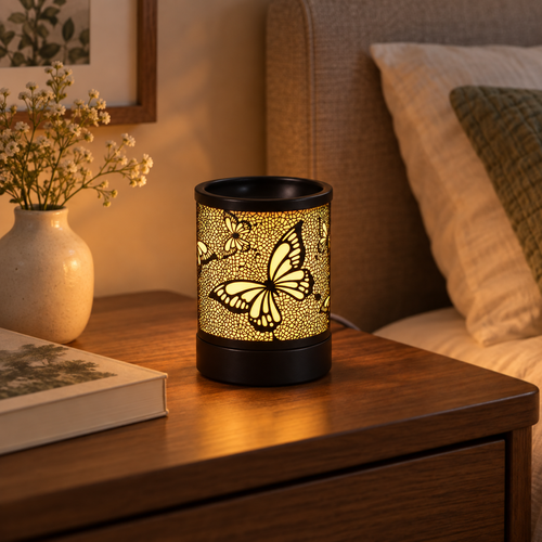 Glowing black butterfly wax warmer on a wooden bedside table beside a book and ceramic vase.