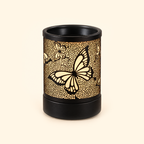 Black butterfly electric wax warmer with a soft amber glow on a warm cream background.