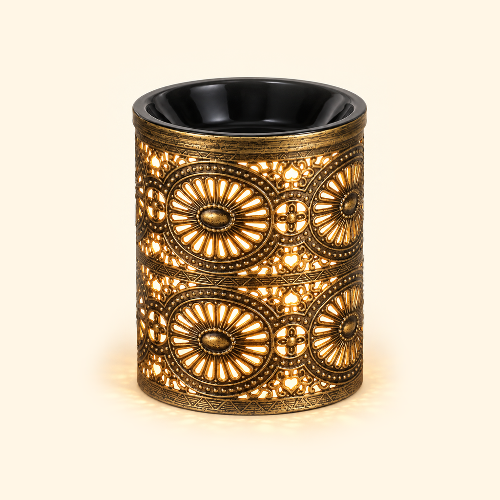 Vintage bronze electric wax warmer glowing with warm amber light through its ornate floral cutout design.