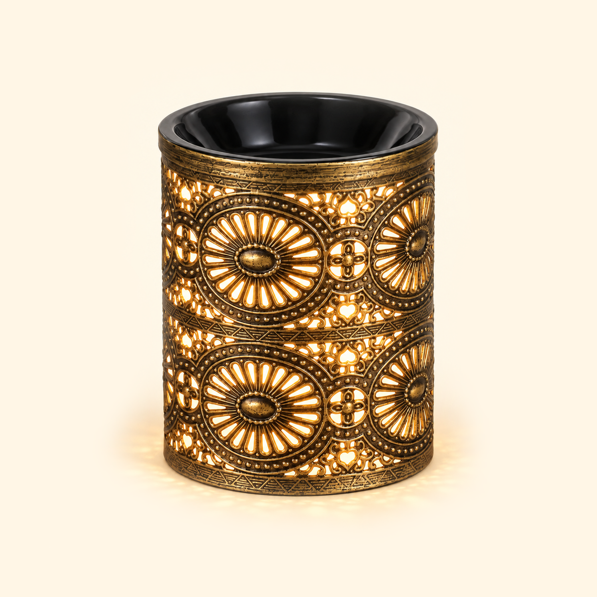 Vintage bronze electric wax warmer glowing with warm amber light through its ornate floral cutout design.