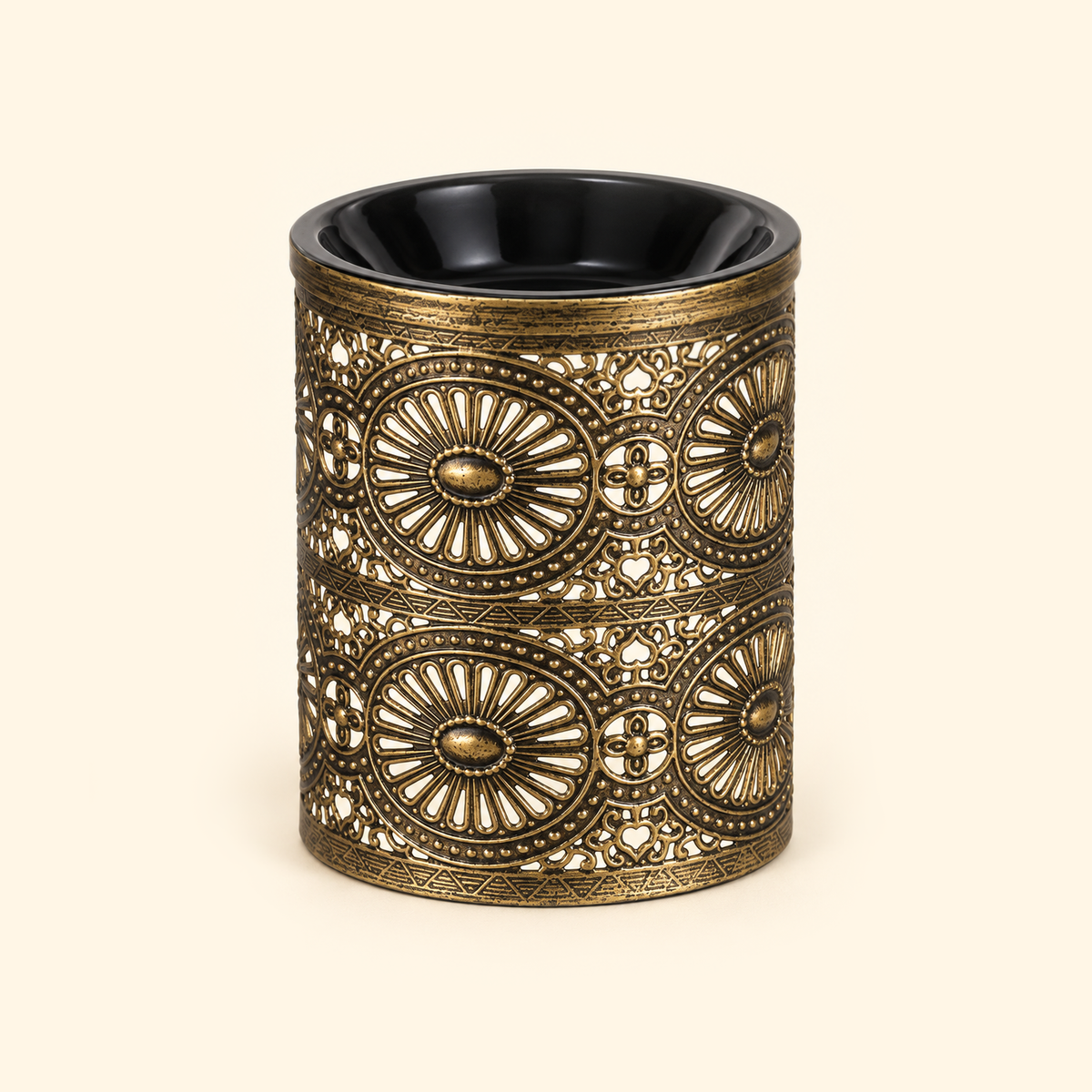 Vintage bronze electric wax warmer with a black dish and ornate floral cutout design, switched off on a cream background.