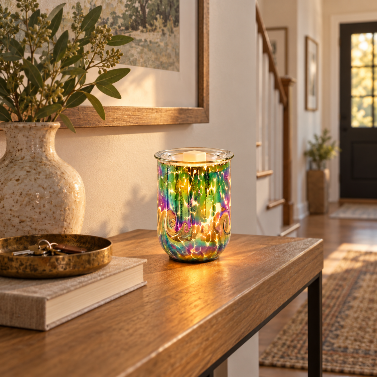 Glowing Multicolor Swirl glass wax warmer on an entryway console beside a vase and decorative tray.