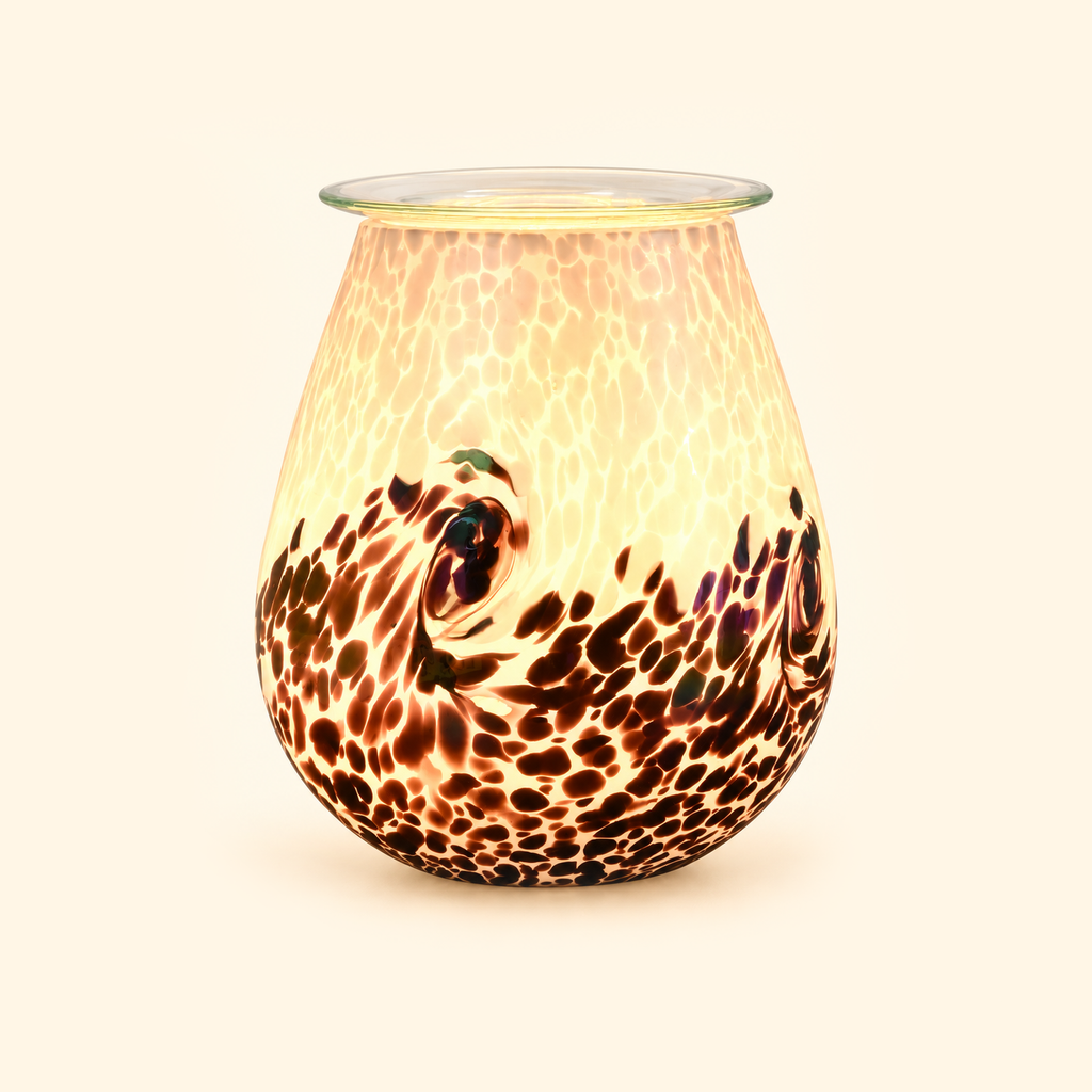 Prismatic Tide glass illumination wax warmer glowing warmly on a cream background.