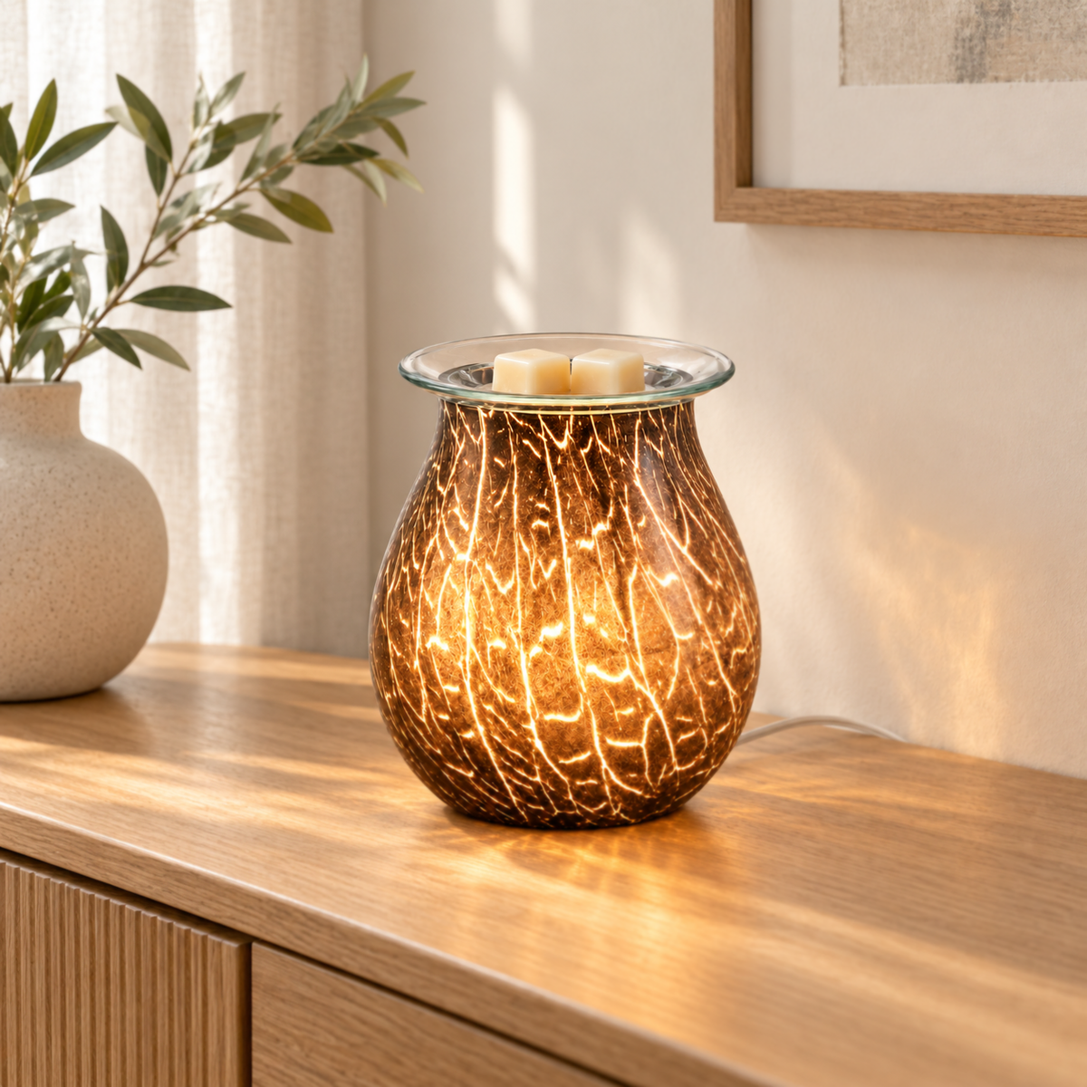 Glowing smoked crackle glass wax warmer with ivory wax melts displayed on a light oak living room sideboard.