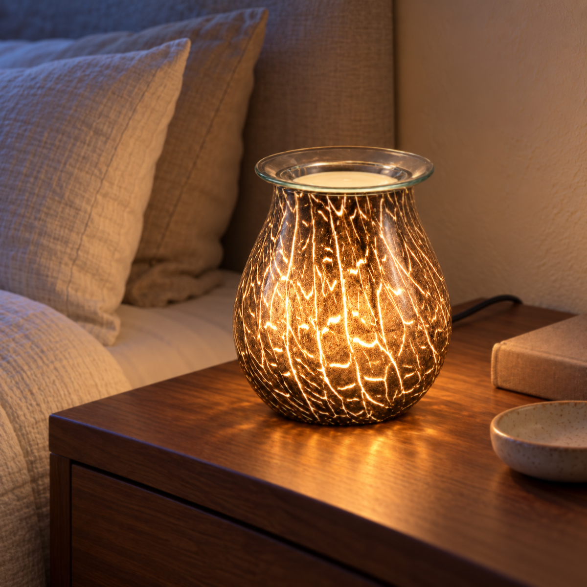 Smoked crackle glass wax warmer casting a warm glow on a walnut bedroom nightstand at dusk.