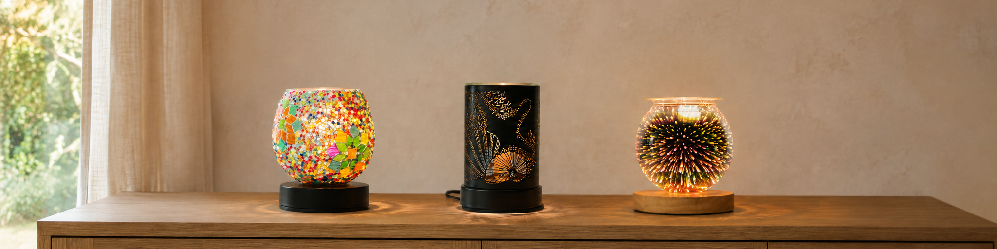 Illumination Wax Warmers collection featuring Mosaic Bloom Globe, Moonlit Reef and Galaxy Firework wax warmers glowing on a wooden sideboard in a warm home interior.