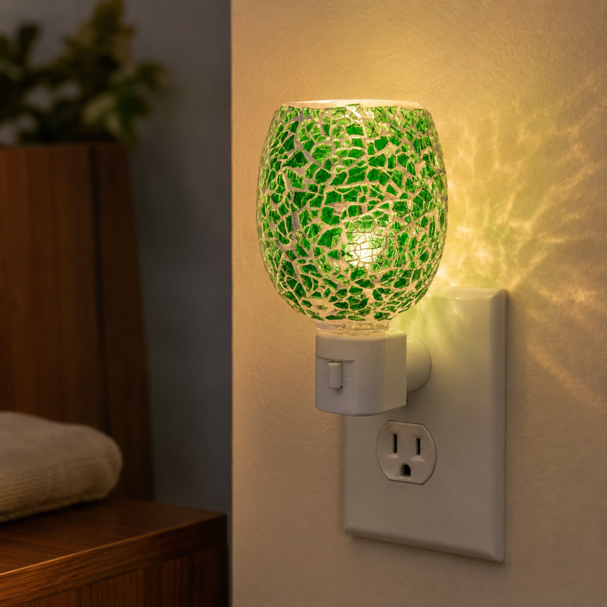 Emerald Mosaic Pluggable Wax Warmer glowing warmly from a wall outlet in a cozy interior.