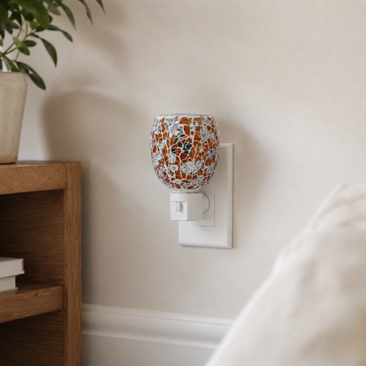 Golden Amber Mosaic electric wax warmer installed in a wall outlet in a warm home interior.