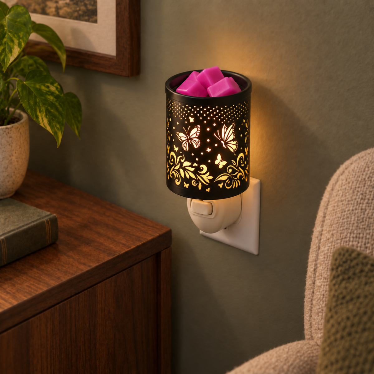 Butterfly Vine plug-in wax warmer glowing warmly from a wall outlet beside a wooden table.