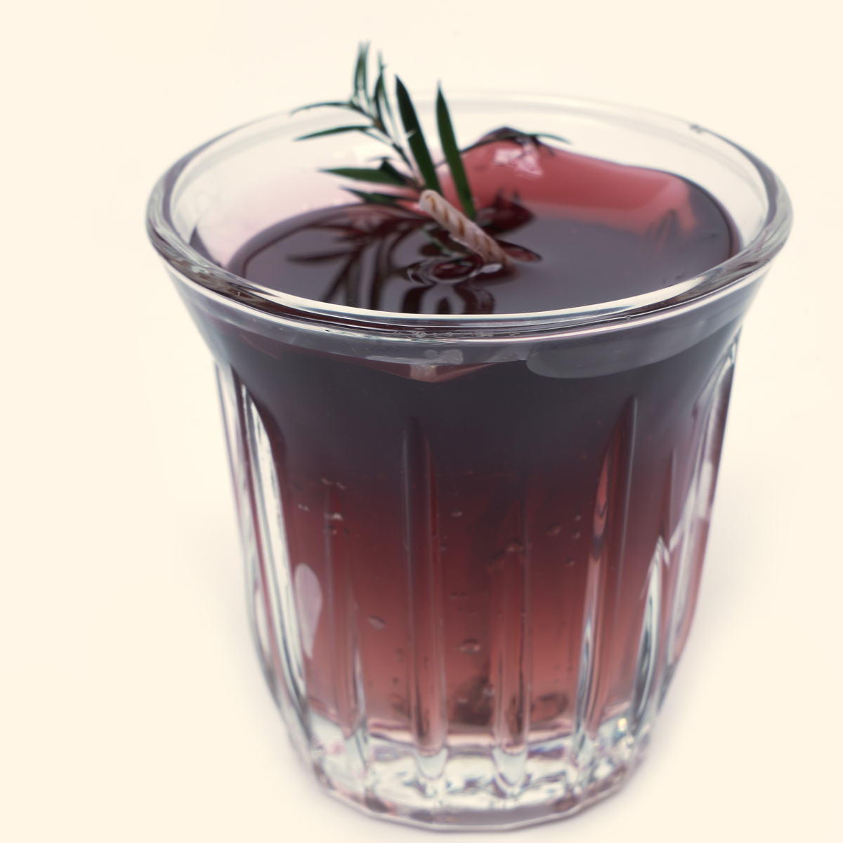 Close-up of the Iced Americano candle showing the glossy dark wax surface, twisted wick, green sprig and translucent ice-cube details.
