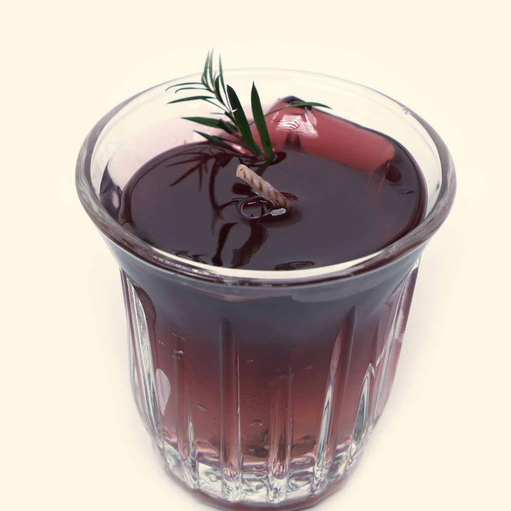 Detail view of the Iced Americano Coffee Candle highlighting the dark translucent wax, twisted wick and green sprig.