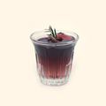 Iced Americano Coffee Candle with dark translucent coffee-colored wax, a twisted wick, green needle-like sprig and ice-cube details in a clear fluted glass cup.