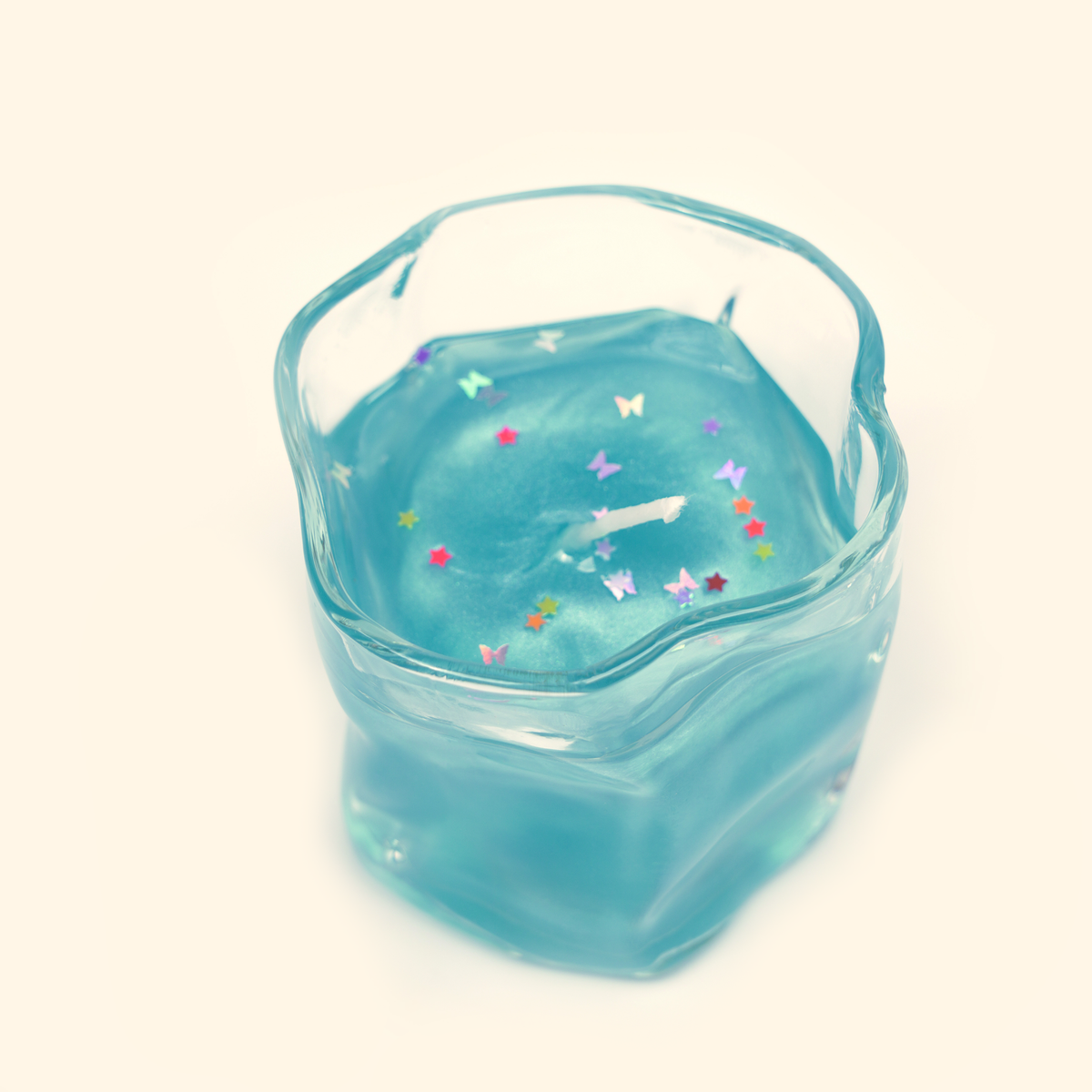 High-angle view of the Ocean Dream Gel Candle showing the white wick, fine shimmer and multicolored star and butterfly confetti.