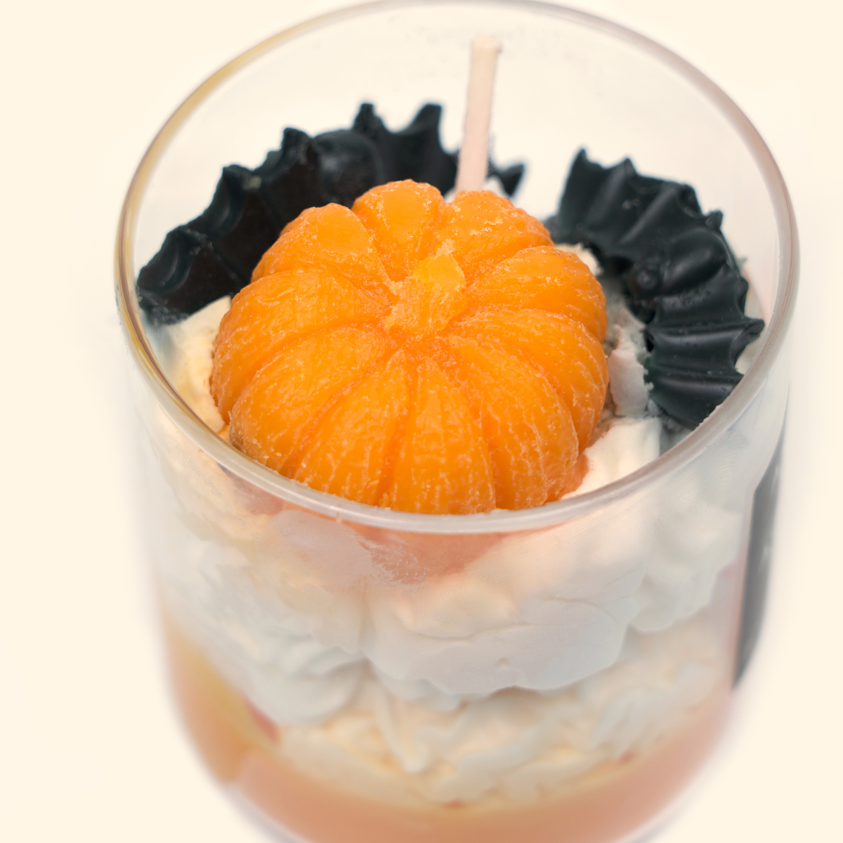 Top close-up of the Halloween candle with a sculpted orange pumpkin, black bat wax decorations and a single white wick.