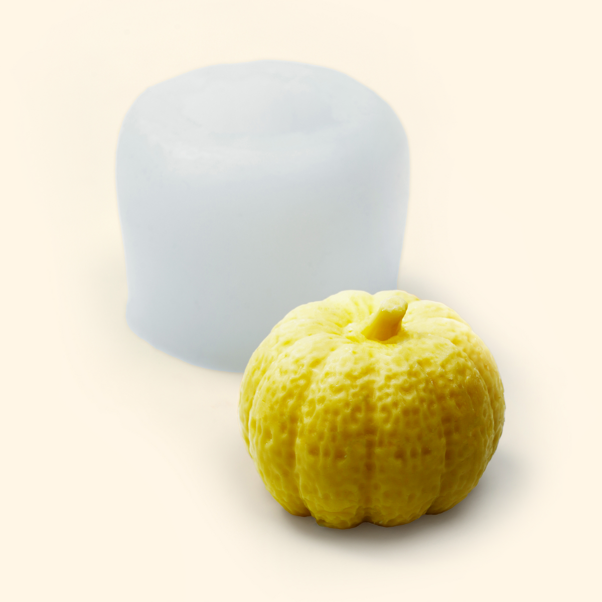 Translucent medium pumpkin silicone mold displayed beside a sample finished wax piece showing the detailed pumpkin shape.