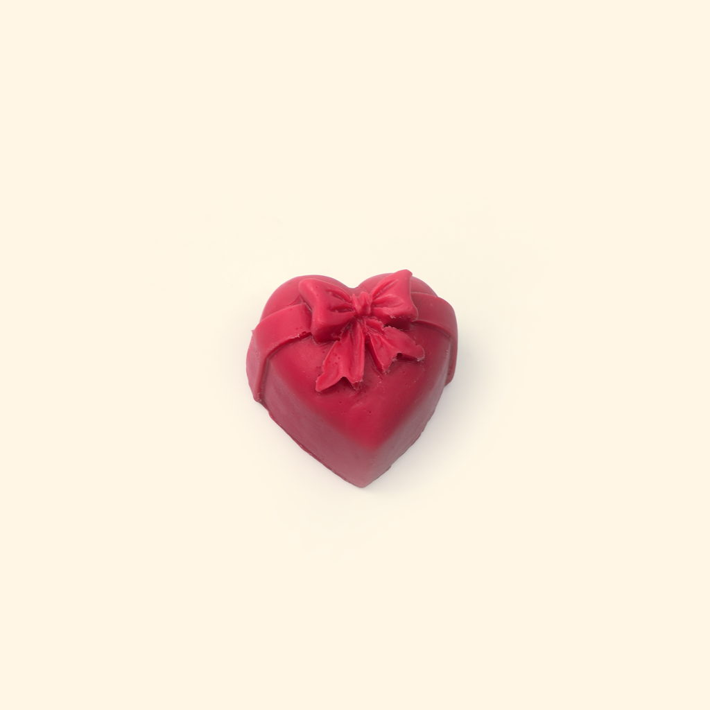 Embossed Bow Heart Silicone Wax Melt Mold shown with a sample heart-shaped wax piece featuring a raised bow and ribbon details.