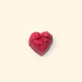 Embossed Bow Heart Silicone Wax Melt Mold shown with a sample heart-shaped wax piece featuring a raised bow and ribbon details.