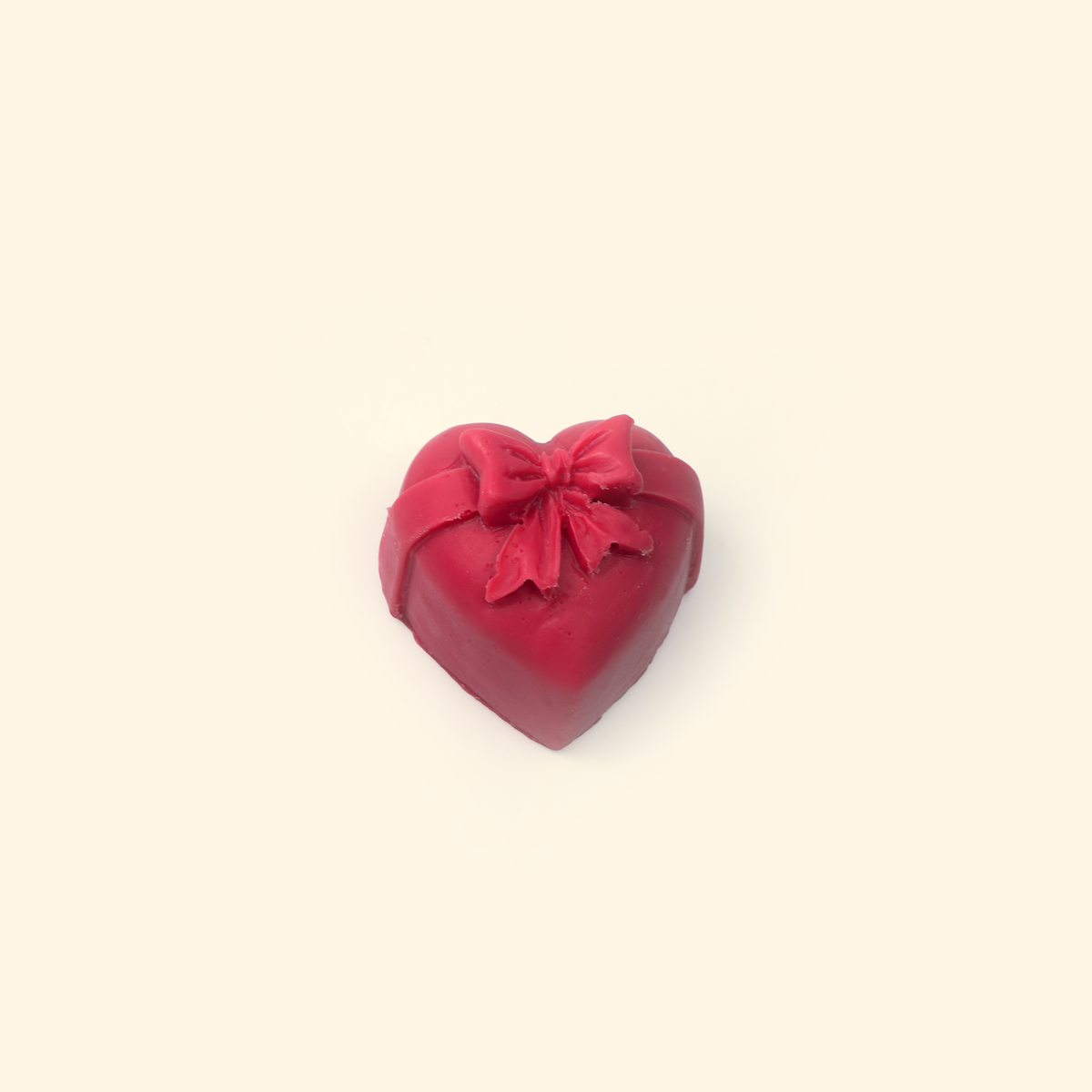 Embossed Bow Heart Silicone Wax Melt Mold shown with a sample heart-shaped wax piece featuring a raised bow and ribbon details.