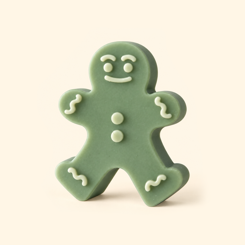 Sage green gingerbread man casting with raised ivory eyes, a smile, two buttons and wavy trim on a cream background.
