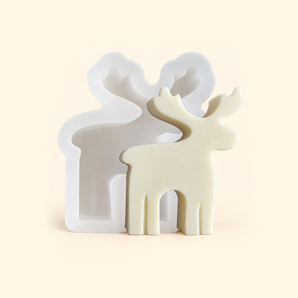 White reindeer silicone mold behind an ivory reindeer casting, showing the recessed cavity and matching antler shape.