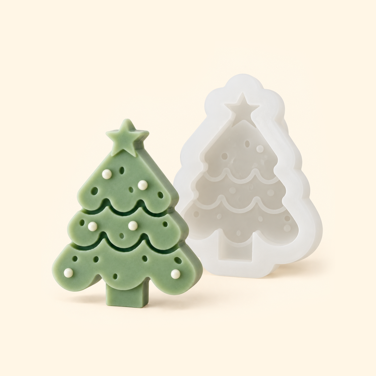 White Christmas tree silicone mold beside a sage green casting with a star topper and white bauble details.