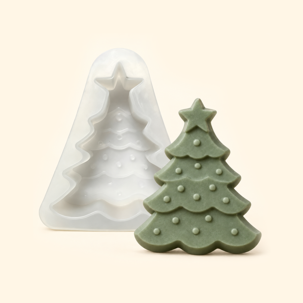 White Christmas tree silicone mold beside a muted green casting with a star topper and raised bauble details.