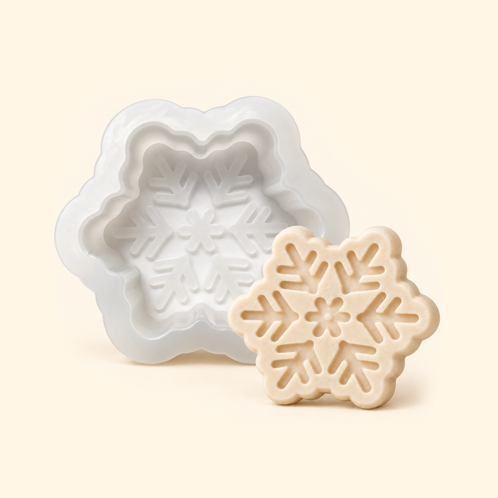 White snowflake silicone mold beside an ivory casting, showing the empty mold cavity and matching snowflake pattern.
