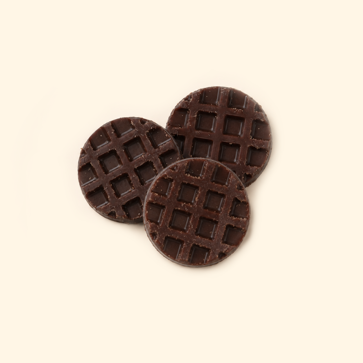 Chocolate Waffle Wax Melts with three round dark brown waffle-shaped pieces overlapping on a light cream background.