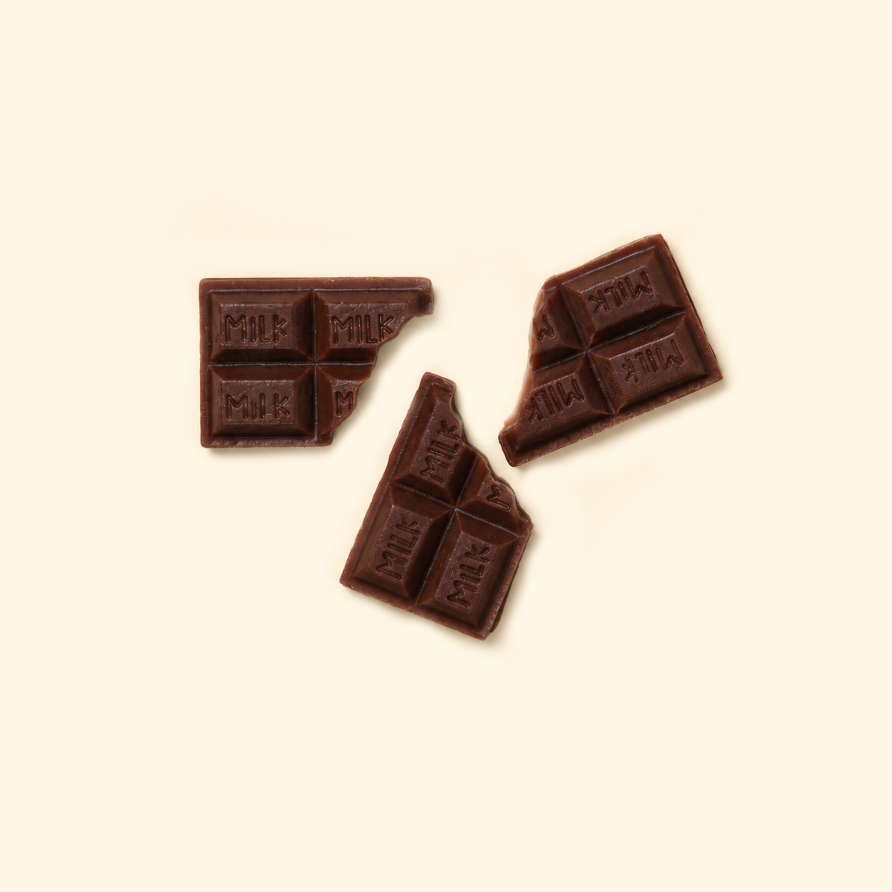 Milk Chocolate Bar Wax Melts with three broken dark brown chocolate-bar-shaped pieces embossed with MILK on a light cream background.
