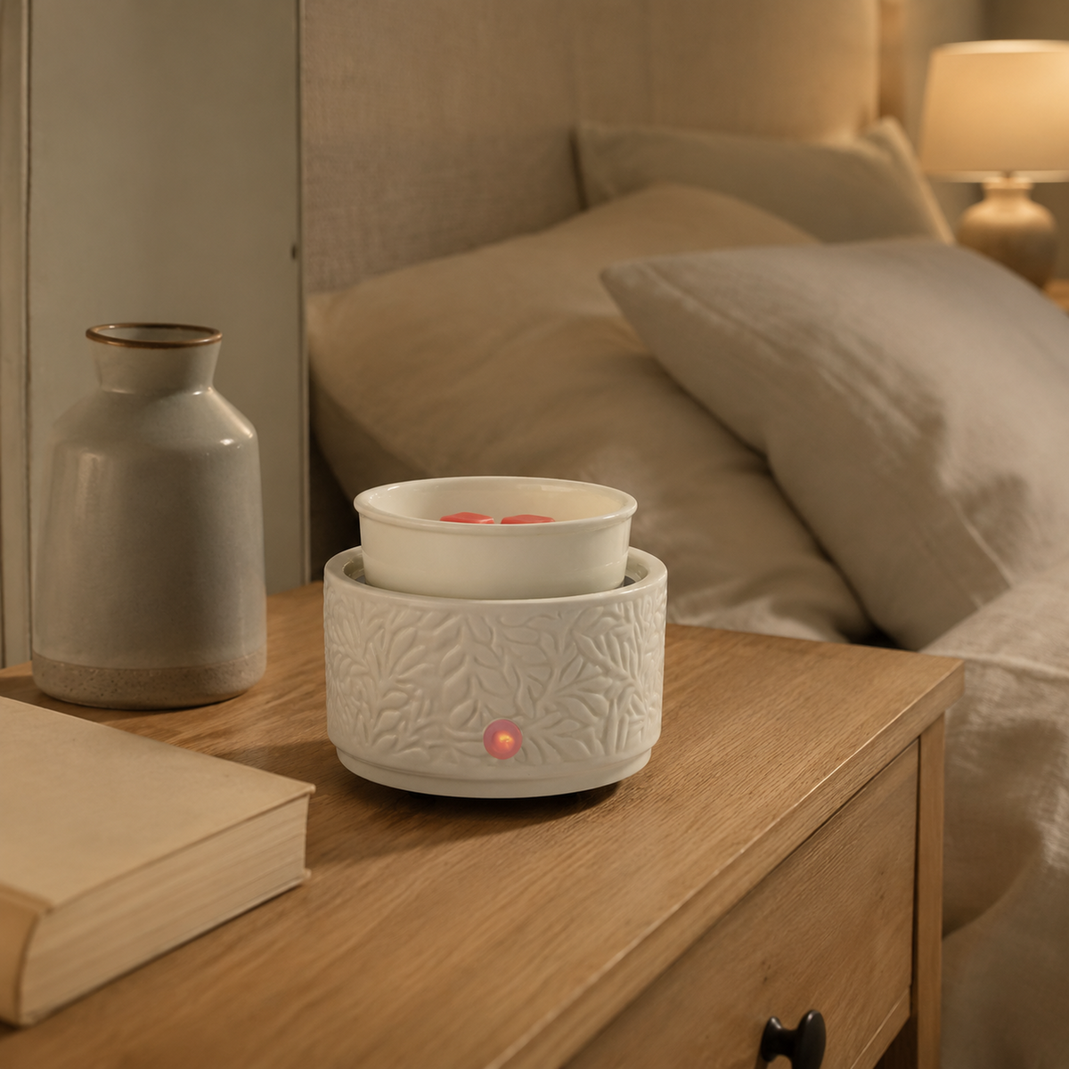 Botanical ceramic wax warmer on a bedroom nightstand with pink wax melts and illuminated control indicator.